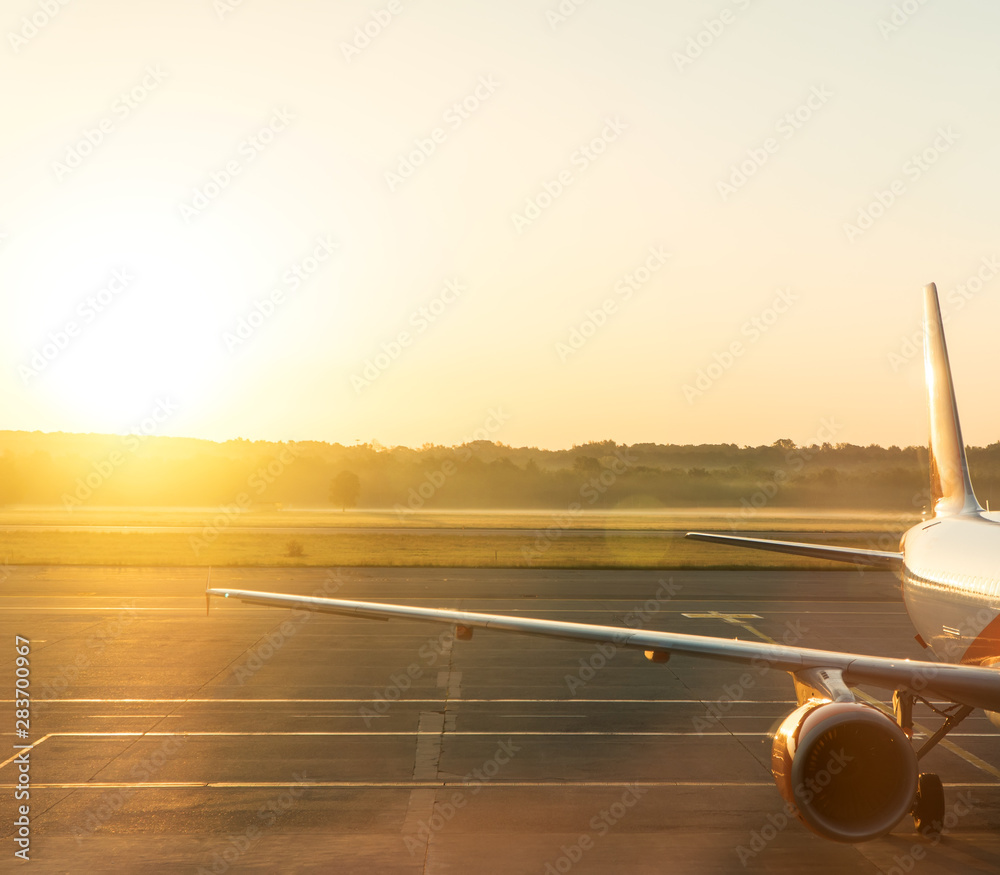 Wall mural Part of airplane on the runway at sunset.