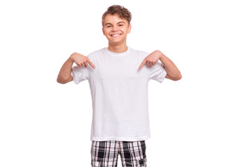 T-shirt design concept. Smiling teen boy in blank white t-shirt, isolated on white background. Mock up template for print. Happy child pointing fingers at blank t-shirt showing empty copyspace.