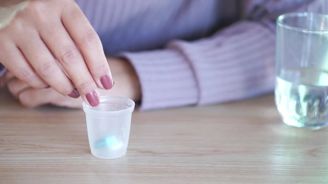 woman hand preparing to take medicine with glass of water and bottle of pill on desk 