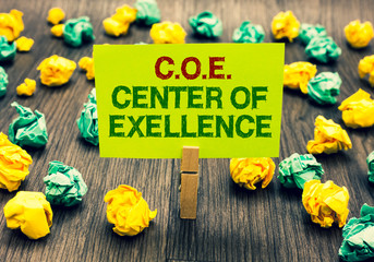 Word writing text C.O.E Center Of Excellence. Business concept for being alpha leader in your position Achieve Clothespin holding yellow note paper crumpled papers several tries mistakes