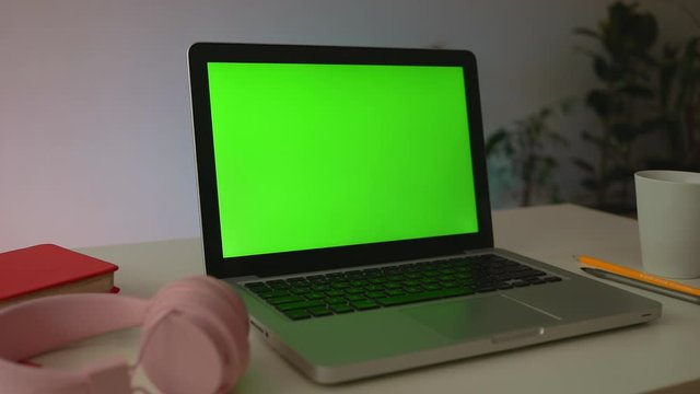A laptop computer with a key green screen set on work office table