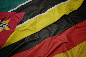 waving colorful flag of germany and national flag of mozambique.