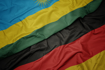 waving colorful flag of germany and national flag of rwanda.