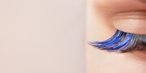 Blue color eyelash extensions. Trendy false lash style close-up, closed eye macro. Wide banner or background with copy space