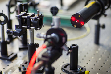Quantum optics lab installations with laser, irises, appertures - laser reflect on optic table un...