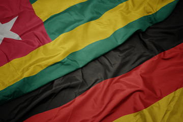 waving colorful flag of germany and national flag of togo.