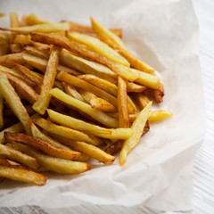 French fries on a white wooden surface, side view. Close-up.