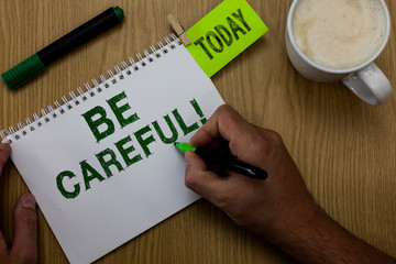 Conceptual hand writing showing Be Careful. Business photo showcasing making sure of avoiding potential danger mishap or harm Man holding marker notebook reminder wooden table cup coffee