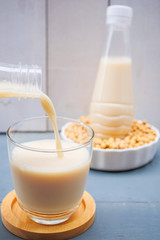 Fototapeta na wymiar Bottle of soy milk and soybean on wooden table