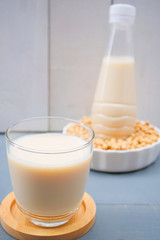 Bottle of soy milk and soybean on wooden table