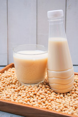 Bottle of soy milk and soybean on wooden table