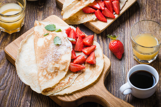 Breakfast or brunch, crepes with fresh summer strawberries and powdered sugar