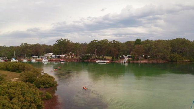 Aerial view of kayaks and moored boats in Currambene Creek, Australia, dolly in.