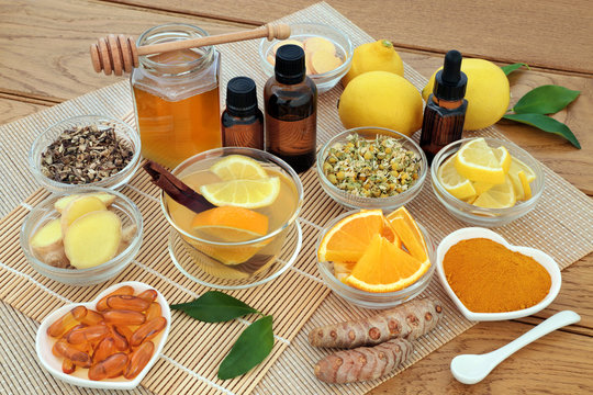 Alternative medicine for cold and flu remedy with hot drink, herbs and spices, lemon and orange fruit, aromatherapy oils, honey, lemon and orange fruit and vitamin tablets on bamboo.