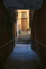 dark alley to the entrance of a yellow old town house in Italy