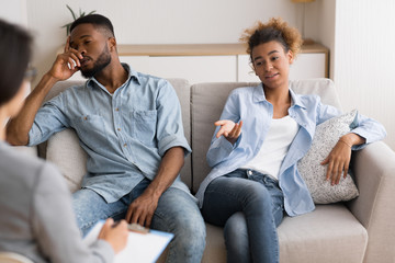 Indifferent Black Spouses Sitting On Sofa At Couples Therapist's Office