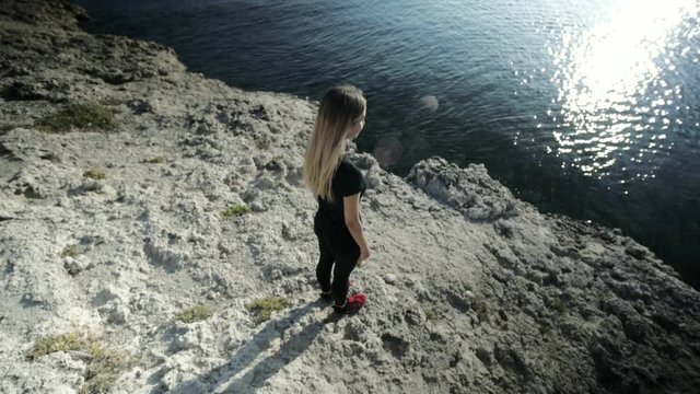Slim attractive caucasian girl standing on rocky beach before practicing yoga. High angle view.