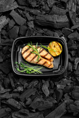 Freshly cooked grill red fish in black delivery box on coal