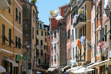 Fototapeta na wymiar Narrow lively street with colorful houses and hanging laundry in the old town of Vernazza, Cinque Terre in Liguria, Italy