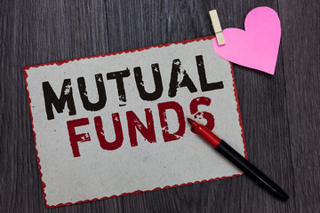 Text sign showing Mutual Funds. Conceptual photo An investment program funded by shareholders Individual Stocks White page red borders marker clothespin holds paper heart wood background