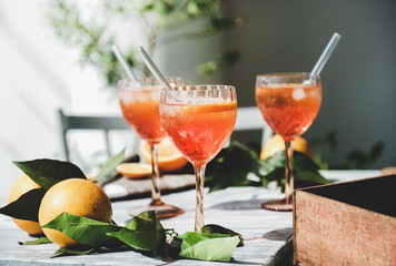 Aperol Spritz aperitif alcohol cocktail in glasses with fresh oranges and ice on grey marble board,...
