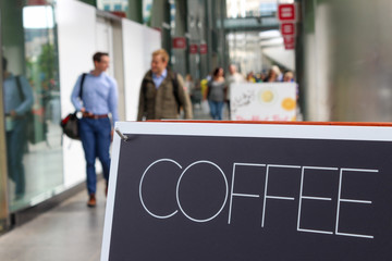 Coffee sign on the street, people walking on the background