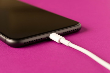 Smartphone on charge . On a purple background. Close up.