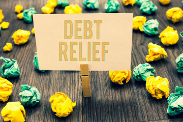 Handwriting text writing Debt Relief. Concept meaning partial or total remission of it especially those by countries Clothespin holding light pink note paper crumpled papers several tries