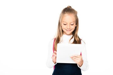 Fototapeta premium cute schoolgirl smiling while using digital tablet isolated on white