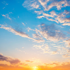 Naklejka na ściany i meble Beautiful dramatic sky at sunrise. Blue and orange colors of the sky with white clouds.