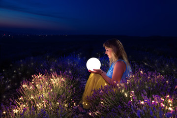 The girl holds the moon in her hands. Lavender field at night.
