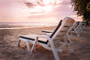Beautiful beach during sunset. Chairs on the sandy beach near the sea. Summer holiday and vacation concept for tourism.