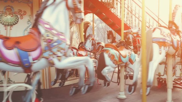 Traditional Vintage Carousel with Colorful Wooden Circus Horses. Merry-go-round in the Carnival Fair Park. Sunset soft light glow in the background. Entertainment, holidays, joy concept.