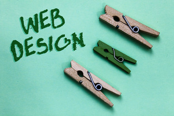 Text sign showing Web Design. Conceptual photo who is responsible of production and maintenance of websites Three brown green vintage clothespins clear background Holding things