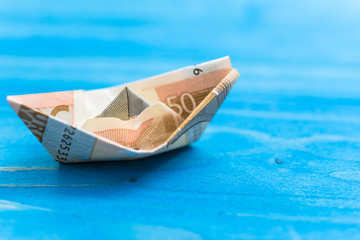 Money ships concept of money in finance. Blue wood background. Nice trip holiday.