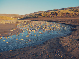 Small river by sand dunes, small cabins in the background. Concept living in remote location by nature.
