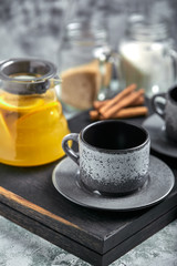 Transparent glass teapot with chitrus tea and cups, tea set on a wooden table. Close up, gray background, soft light.