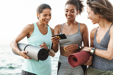 Three cheerful young sport girls standing at the beach