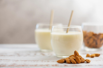 Almond milk in glasses with almond on a light wooden table