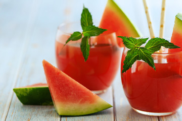 Watermelon smoothie in glass with fresh watermelon slices on light background