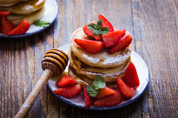 Breakfast or brunch, pancakes with fresh summer strawberries, powdered sugar, honey