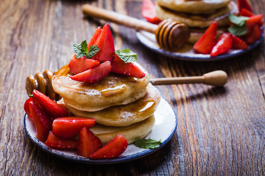 Breakfast or brunch, pancakes with fresh summer strawberries, powdered sugar, honey