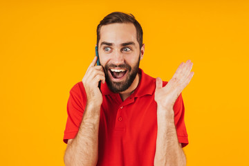 Portrait of excited man in red t-shirt smiling and talking on smartphone