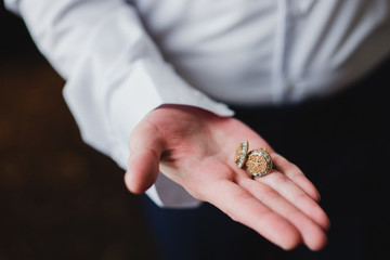 Wedding fashion for men. Closeup of caucasian man holding the cufflinks in his hand.