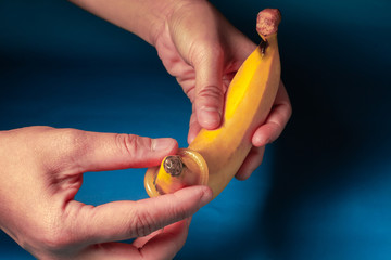 Close up shot of condom ready to use in  hand Wear on the banana . give condom to safe sex concept...