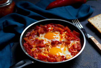 Shakshouka or shakshuka, eggs in a sauce of tomatoes and peppers, dark blue background, copy space for your text