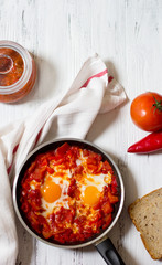 Shakshouka or shakshuka, eggs in a sauce of tomatoes and peppers, top view, light  background, copy space for your text