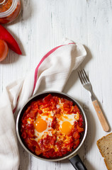 Shakshouka or shakshuka, eggs in a sauce of tomatoes and peppers, top view, light  background, copy space for your text