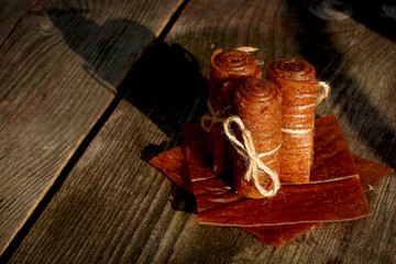 Handmade apple pastilles rolls with linen thread lined with leaf marshmallows on wooden background