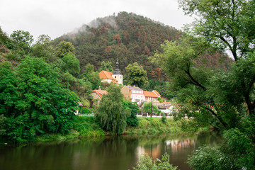 Fototapeta na wymiar Ancient church by the river in mountainous countryside on a cloudy day